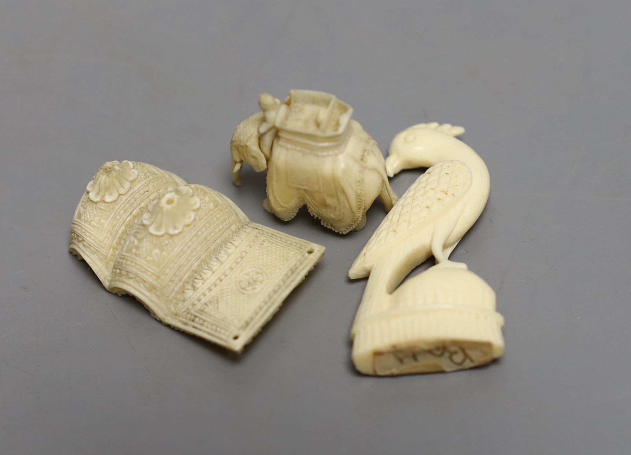 A 19th century Indian carved ivory of figures on a caparisoned elephant, 8.5cm tall, and two other small ivory carvings